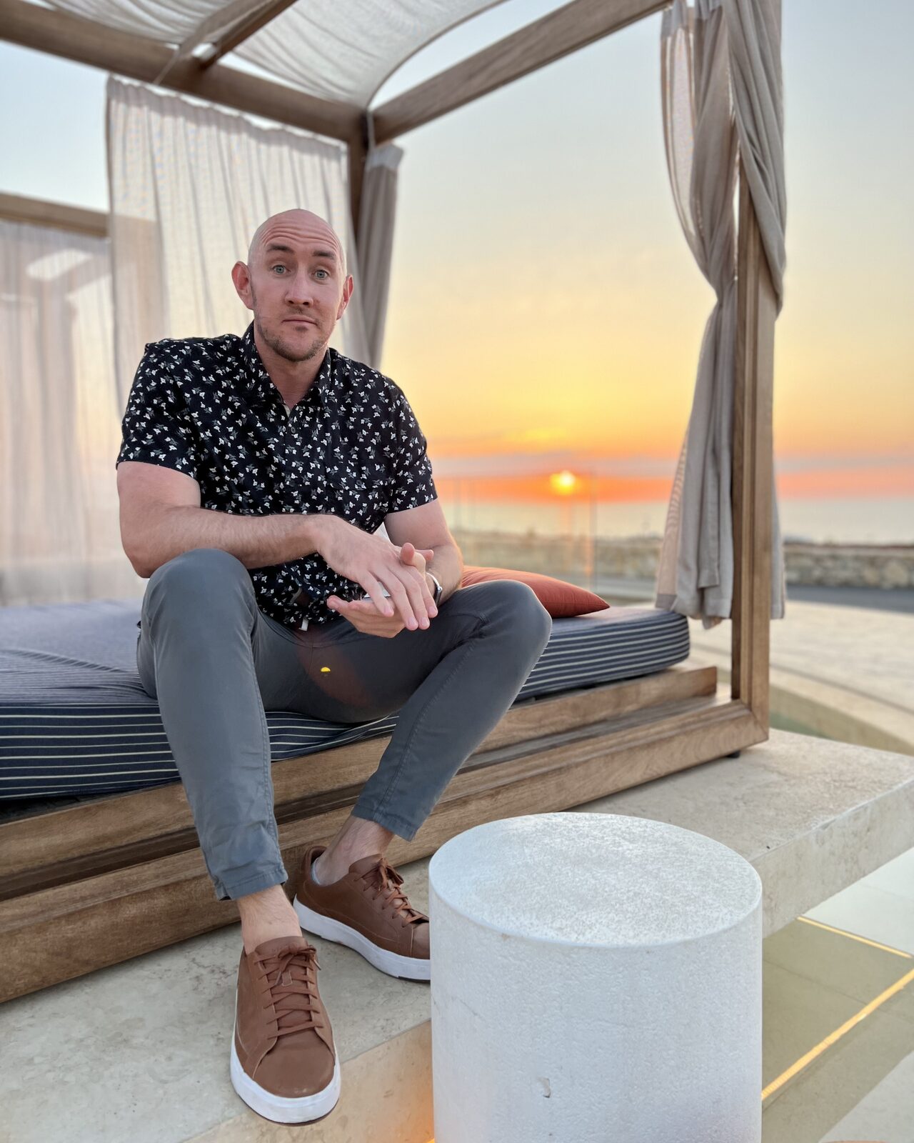 Jason Zook sitting on a cliffside daybed at sunset, Portugal
